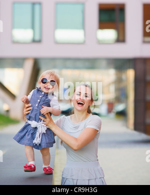 Madre sorridente giocando con il bambino in città Foto Stock