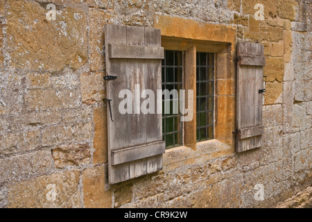 Tapparelle su windows impostato nel vecchio Cotswold muro di pietra Foto Stock