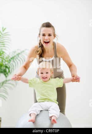 Mother holding baby sitting sulla sfera di fitness Foto Stock