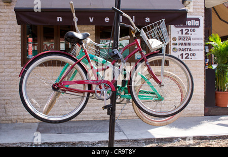 Due biciclette legato fino in alto su un montante metallico al di fuori di un ristorante con un po' di Italia mentre il marciapiede è in riparazione Foto Stock