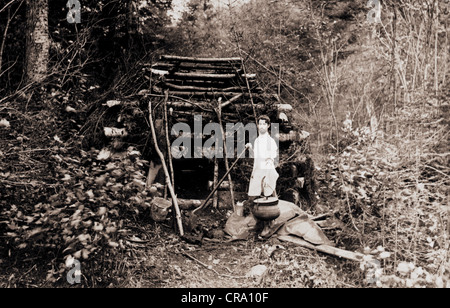 Giovane alla primitiva di magra a Log Cabin nel bosco Foto Stock