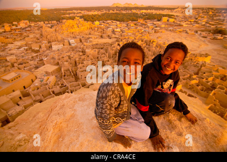 Due ragazzi sorridenti di fronte alla rovina della città di Shali, Siwa, Egitto, Africa Foto Stock