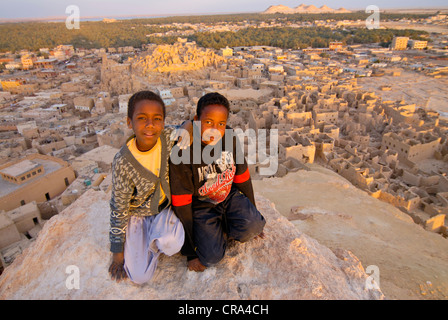 Due ragazzi sorridenti di fronte alla rovina della città di Shali, Siwa, Egitto, Africa Foto Stock