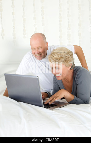 Coppia di anziani utilizzando laptop sul letto Foto Stock
