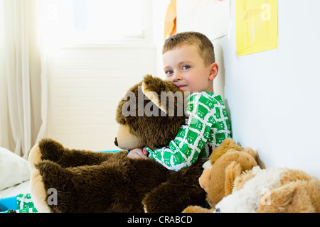 Ragazzo abbracciando Teddy bear a letto Foto Stock