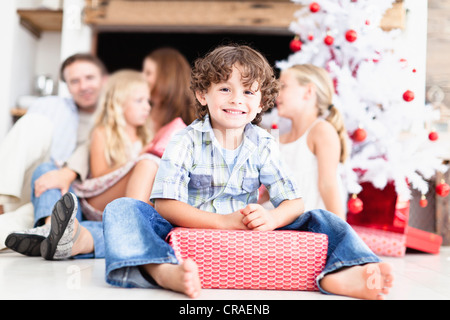 Ragazzo seduto con avvolto un regalo di Natale Foto Stock