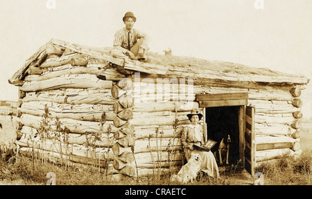 Giovane uomo & donna a Windowless grezzo Log Cabin Foto Stock