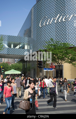 Pedoni che attraversano Huaihua Street nel centro di Shanghai accanto alla sistemazione di negozio di Cartier in Cina Foto Stock