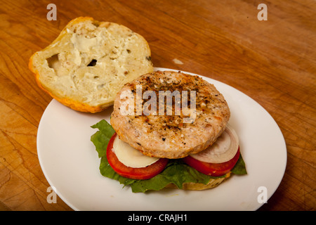 Una Turchia hamburger su un formaggio e bagel jalapeno con fette di cipolla e pomodoro su un letto di lattuga romana Foto Stock