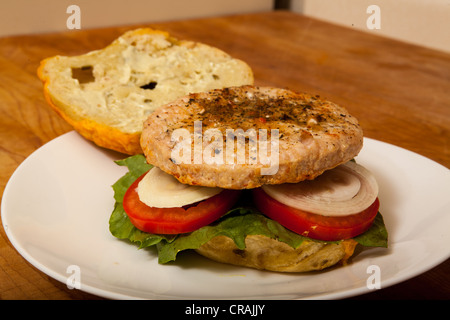 Una Turchia hamburger su un formaggio e bagel jalapeno con fette di cipolla e pomodoro su un letto di lattuga romana Foto Stock