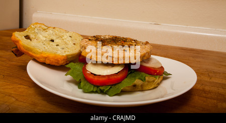 Una Turchia hamburger su un formaggio e bagel jalapeno con fette di cipolla e pomodoro su un letto di lattuga romana Foto Stock