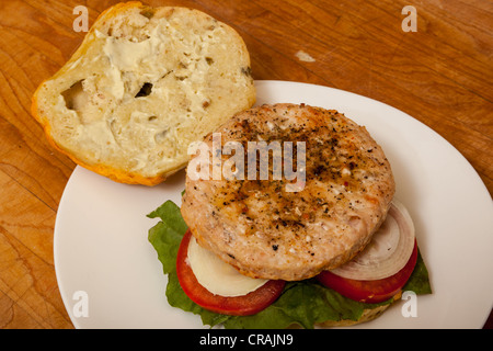 Una Turchia hamburger su un formaggio e bagel jalapeno con fette di cipolla e pomodoro su un letto di lattuga romana Foto Stock