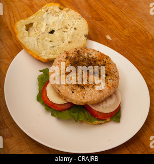 Una Turchia hamburger su un formaggio e bagel jalapeno con fette di cipolla e pomodoro su un letto di lattuga romana Foto Stock