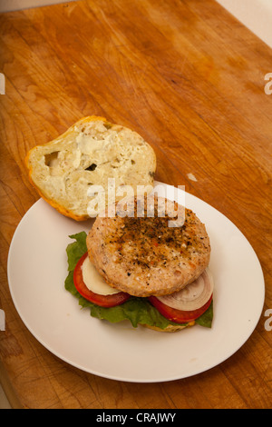 Una Turchia hamburger su un formaggio e bagel jalapeno con fette di cipolla e pomodoro su un letto di lattuga romana Foto Stock