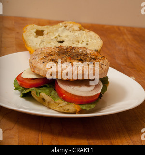 Una Turchia hamburger su un formaggio e bagel jalapeno con fette di cipolla e pomodoro su un letto di lattuga romana Foto Stock