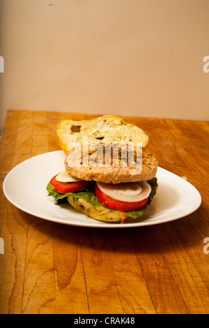 Una Turchia hamburger su un formaggio e bagel jalapeno con fette di cipolla e pomodoro su un letto di lattuga romana Foto Stock