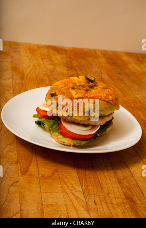 Una Turchia hamburger su un formaggio e bagel jalapeno con fette di cipolla e pomodoro su un letto di lattuga romana Foto Stock