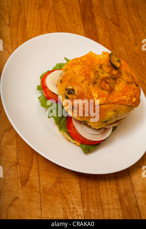 Una Turchia hamburger su un formaggio e bagel jalapeno con fette di cipolla e pomodoro su un letto di lattuga romana Foto Stock