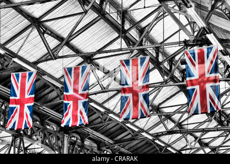Union Jack appeso bandiere a Londra la stazione ferroviaria di Victoria. Monocromatico con spot bandiere colorate Foto Stock