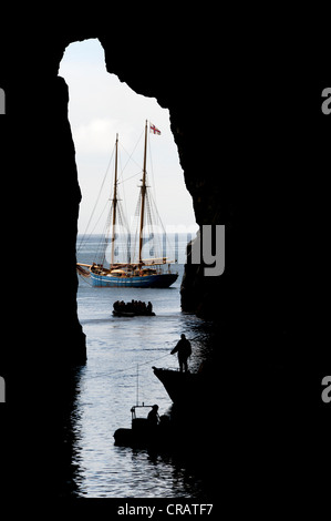 Vista dall'interno di una grotta verso una nave a vela, Norðlýsið, Hestur, Isole Faerøer, Atlantico del Nord Foto Stock