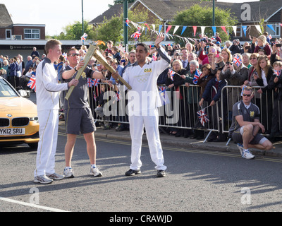 Hani Macki un Omani portatore di torcia le mani sopra la fiamma olimpica a Martin Dauber in Marske dal mare Cleveland UK del 18 giugno Foto Stock