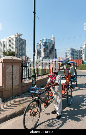 In rickshaw drivers di fronte a nuove zone residenziali alti edifici in Gurgaon, Haryana, India, Asia Foto Stock