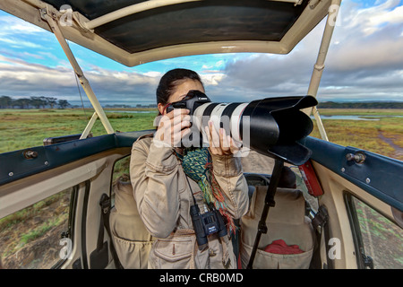 Giovane fotografo di scattare le foto da un safari bus, Lake Nakuru National Park, Kenya, Africa Orientale, PublicGround Foto Stock