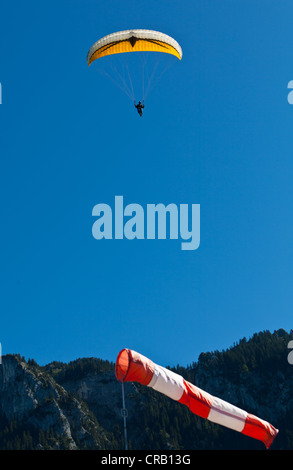 Di atterraggio di parapendio contro il vento con una manica a vento, nella parte anteriore del Tegelberg Mountain, Alta Baviera, Baviera, PublicGround Foto Stock