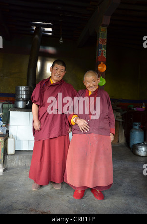 Due monache buddiste, una donna di mezza età, una donna anziana, 70 anni, indossare vesti rosso all'ingresso del monastero Foto Stock