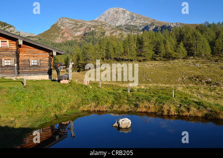 Cabina in legno si riflette in un piccolo stagno, Gotzenalm alp, Schoenau, Koenigssee, Berchtesgadener Land Baviera, Germania, Europa Foto Stock