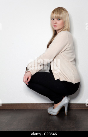 Giovane donna bionda in posa mentre squatting Foto Stock