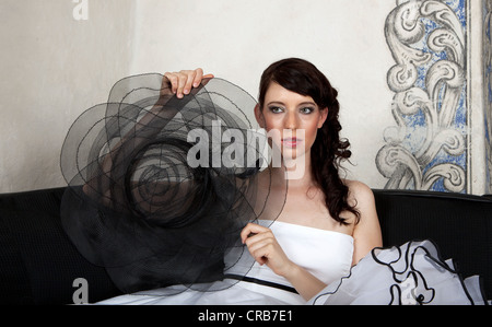 Giovane donna tenendo un cappello e indossa un abito bianco Foto Stock