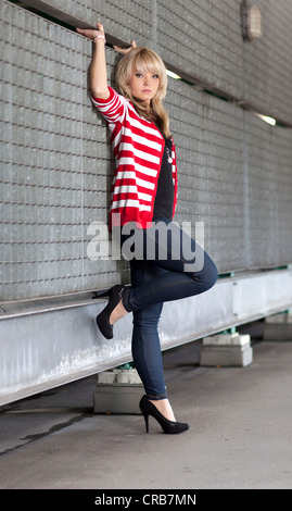 Giovane donna bionda jeans blu e un rosso-bianco striato cardigan Foto Stock
