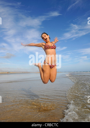 Giovane donna il taglio di un cappero dal mare, simbolico per godersi la vita, Whitehaven Beach, Whitsunday Island Foto Stock