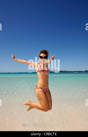 Giovane donna il taglio di un cappero dal mare, simbolico per godersi la vita, Whitehaven Beach, Whitsunday Island Foto Stock