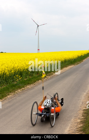 Recumbent bicicletta davanti a un campo di canola, turbina eolica, impianto di energia eolica, Hesse, Germania, Europa Foto Stock