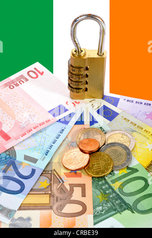 Serratura a combinazione sulle banconote e monete in euro di fronte alla bandiera nazionale dell'Irlanda, immagine simbolica per valuta la sicurezza Foto Stock