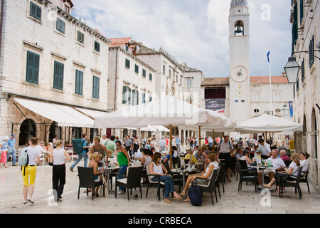 I turisti seduti in un caffè all'aperto, o Stradun Placa street, clock tower, Dubrovnik, Dalmazia, Croazia, Europa Foto Stock
