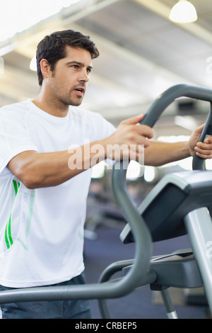 Uomo con macchina ginnica in palestra Foto Stock