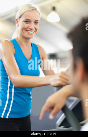 Donna che utilizza macchina ginnica in palestra Foto Stock