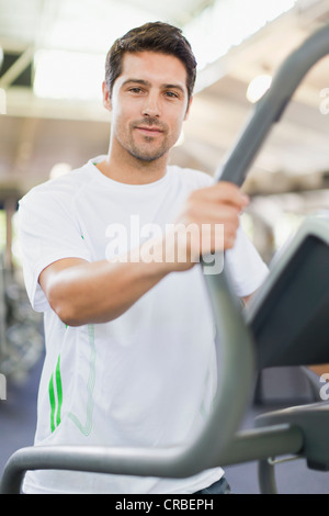 Uomo con macchina ginnica in palestra Foto Stock