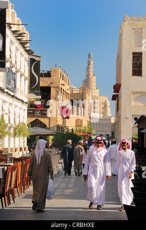 Pedoni nel Souq Waqif con la torre del Qatar centro culturale islamico, FANAR, Doha, Qatar, Medio Oriente Foto Stock