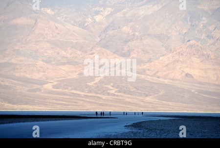 I turisti a sunrise in salina di base Badwater, gamma Panamint sul retro, il Parco Nazionale della Valle della Morte, Deserto Mojave Foto Stock