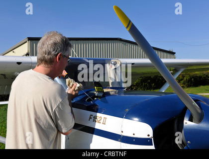 Pilota di controllo dell'olio motore di un Cessna 152 prima di un volo, aeroporto Hahnweide, Kirchheim unter Teck, Baden-Wuerttemberg Foto Stock