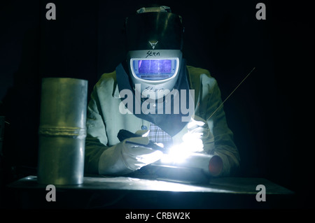 Saldatrice industriale indossando indumenti di protezione sul luogo di lavoro Foto Stock