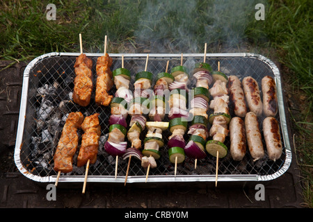 Monouso per barbecue a carbone per la cottura di spiedini e salsicce. Foto Stock