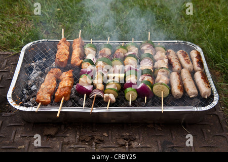 Monouso per barbecue a carbone per la cottura di spiedini e salsicce. Foto Stock