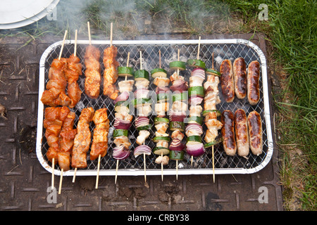 Monouso per barbecue a carbone per la cottura di spiedini e salsicce. Foto Stock