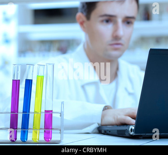 Oung ricercatore maschio di effettuare attività di ricerca scientifica in un laboratorio Foto Stock