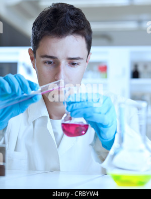 Oung ricercatore maschio di effettuare attività di ricerca scientifica in un laboratorio Foto Stock